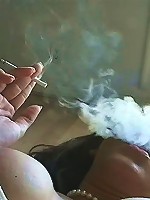 A smokin gal bedecked in pearls emits smoke curls into the air around her as she lounged half naked while enjoying her tobacco.