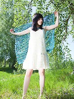 Enchanting brunette babe with a perfect white skin enjoys posing naked on a green meadow.