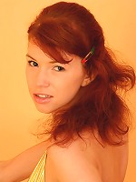 Pretty redhead in gold bikini playing with baby oil