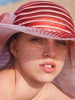 Arina wears a wide-brimmed hat while out nude sunbathing